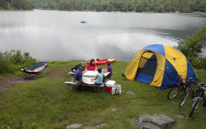 family camping with a tent on the shore of a lake with bikes