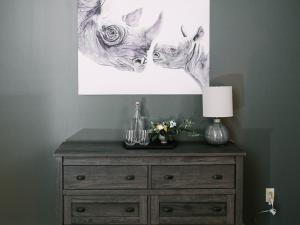 Wooden dresser in a guest room at the Long Neck Inn with a wall hanging picture of a mother and baby rhinoceros 