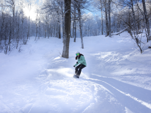 girl snowboarding in woods