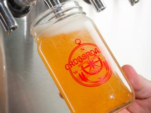 Pouring beer into a Crossroads Brewing Company glass from a tap