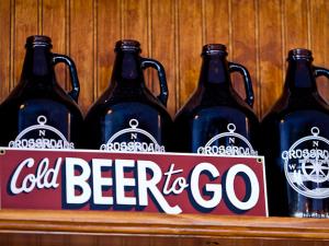 Cold Beer to Go sign with Crossroads Brewing Company growlers in background