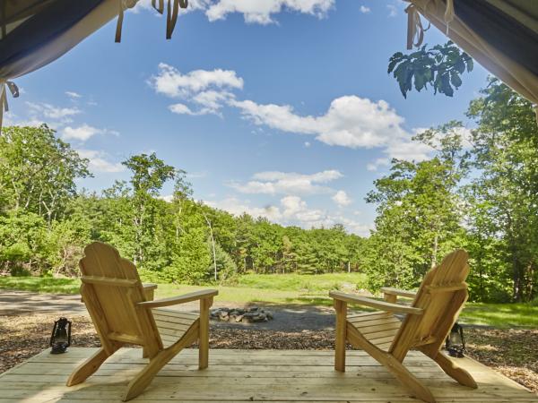 Wooden chairs overlooking a firepit from a glamping cabin