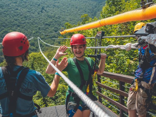 two girls high five at zipline