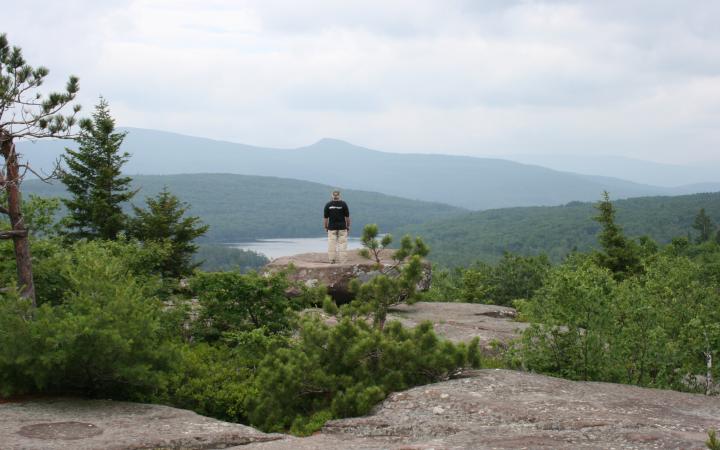Person at the summit of the Escarpment Trail enjoying the view of the Catskill Mountains in the distance